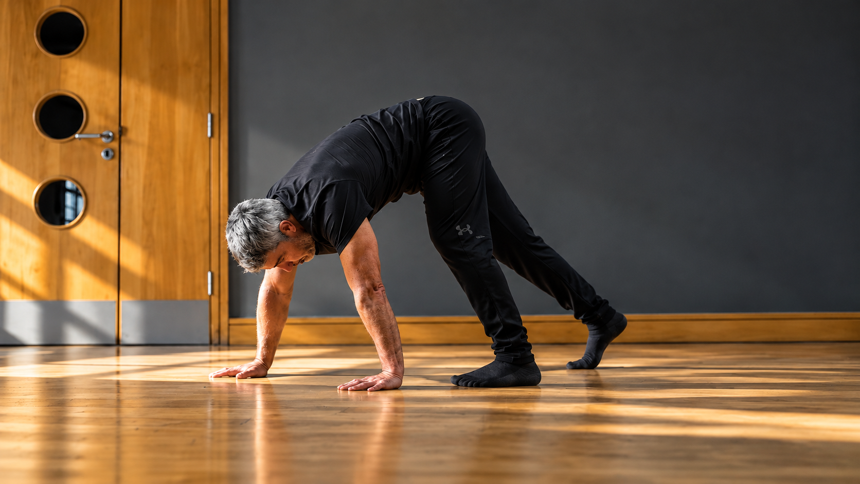 Eugene practising a primal movement on all fours on a wooden studio floor