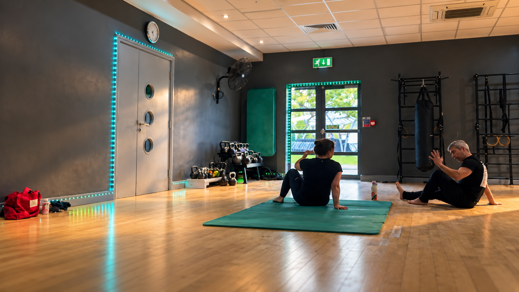 Eugene coaching a member through a floor exercise on a mat in the NBM studio